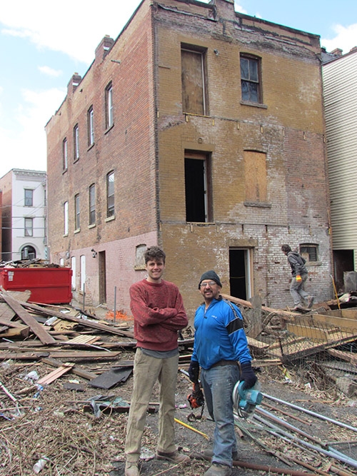 two people stand in front of a run-down building